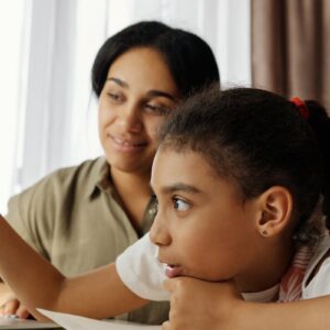 Mother and daughter engaged in online learning at home, using a laptop.